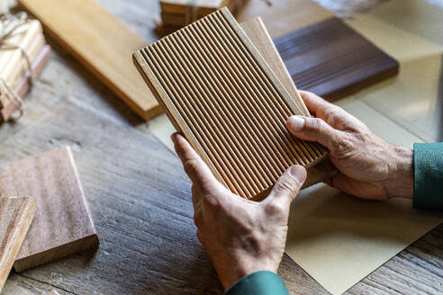 Hands of businessman holding wooden samples in office - DLTSF03757