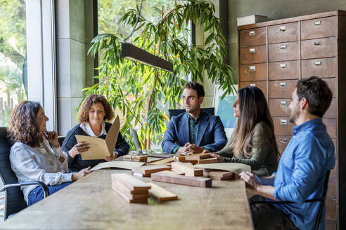 Kreative Fachleute diskutieren über Holzmuster auf dem Schreibtisch im Büro - DLTSF03763