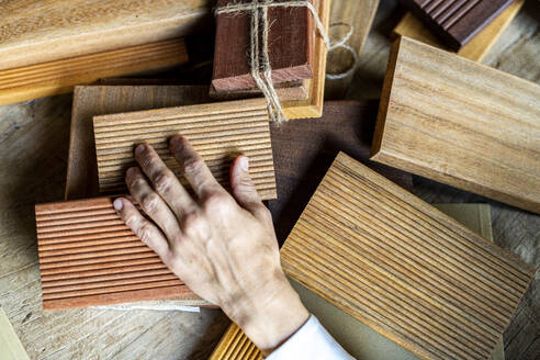 Hand of mature businesswoman choosing wooden samples on desk - DLTSF03768