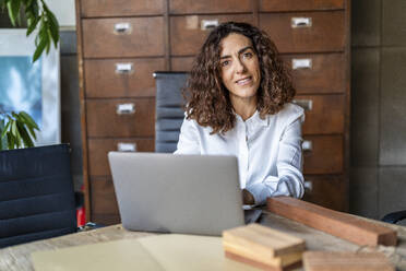 Geschäftsfrau sitzt mit Laptop im Büro - DLTSF03774