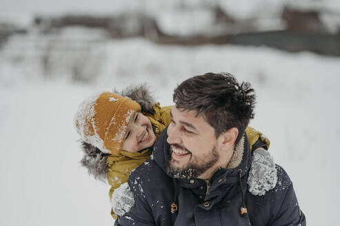 Glücklicher Mann, der mit seinem Sohn im Winter im Schnee Spaß hat - ANAF02723