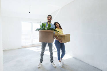 Ein glückliches junges Paar steht mit Kartons in seinem neuen Zuhause - AAZF01552