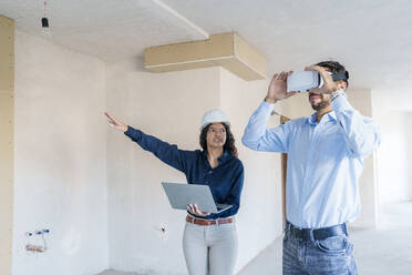 Immobilienmakler zeigt Kunden Renovierungsideen für ein neues Haus in einem Virtual-Reality-Simulator - AAZF01563