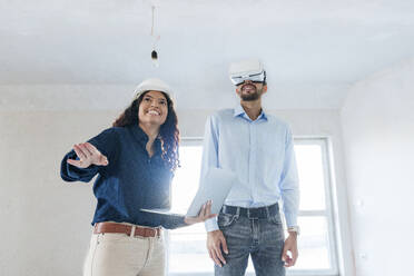 Mann trägt Virtual-Reality-Simulator in der Nähe von Immobilienmakler zeigt neues Haus - AAZF01565