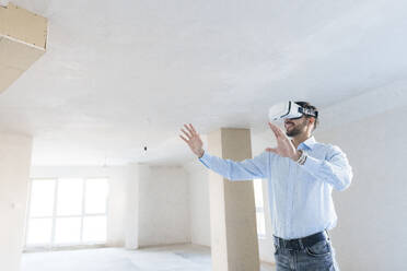 Mann trägt Virtual-Reality-Simulator, um künftige Renovierungsarbeiten am neuen Haus zu inspizieren - AAZF01566