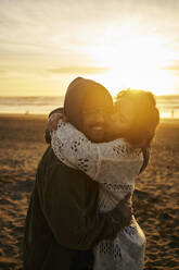 Woman kissing smiling man at beach - ANNF00947