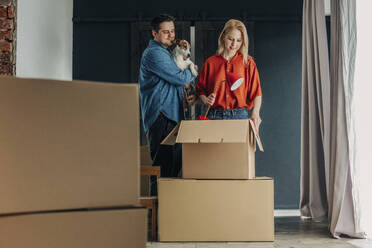 Mann hält Hund mit Frau, die Lampe in Schachtel verpackt - VSNF01671