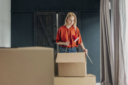 Blonde Frau packt Lampe in Schachtel zu Hause - VSNF01683