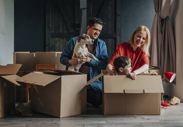 Glückliche Eltern mit Sohn, der zu Hause in einer Kiste sitzt - VSNF01685