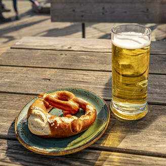 Germany, Bavaria, Oberstdorf, Pretzel, and glass of beer on wooden table - MHF00763
