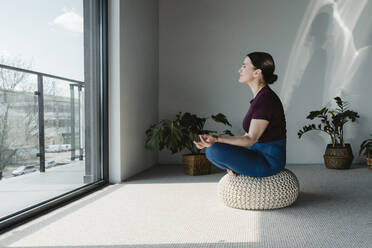 Frau meditiert auf einem Sitz zu Hause - OSF02414