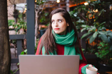 Freiberufler sitzt in der Nähe von Laptop mit Kaffeetasse in der Hand im Cafe - AMWF02009