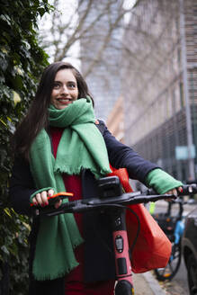 Lächelnde Frau steht mit Elektrofahrrad in der Stadt - AMWF02018