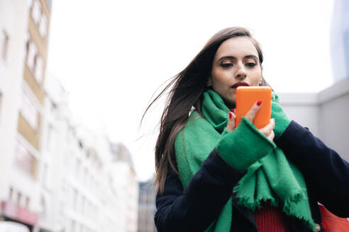 Woman wearing scarf and using smart phone - AMWF02024