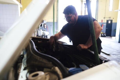 Automechaniker bei Arbeiten am Automotor in der Werkstatt - ASGF04902