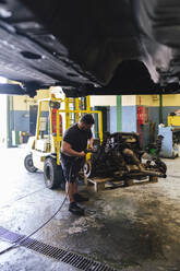 Mechaniker zerlegt Motor mit Schlagschrauber in der Werkstatt - ASGF04907