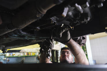 Mechaniker bei der Demontage von Fahrzeugteilen in der Werkstatt - ASGF04922