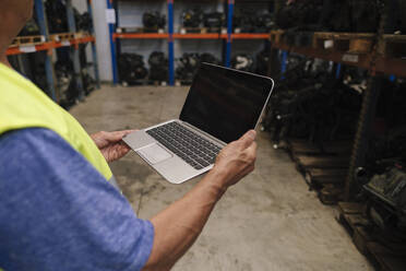 Älterer Automechaniker mit Laptop im Lager - ASGF04934