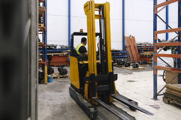 Mechanic sitting in forklift at workshop - ASGF04937