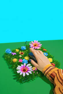 Hand einer Geschäftsfrau, die eine Computermaus auf Frühlingsblumen hält - RDTF00003