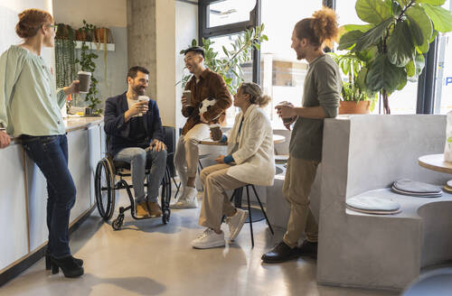 Gemischtrassige Geschäftskollegen genießen einen Kaffee im Bürocafé - JCCMF11297