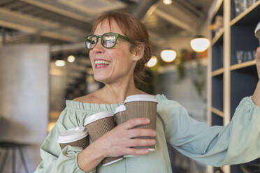 Glückliche Geschäftsfrau hält Einweg-Kaffeebecher im Büro-Café - JCCMF11298