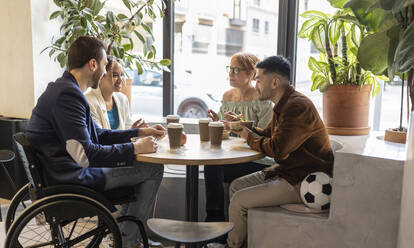 Diverse business colleagues having food at lunch break in office cafe - JCCMF11307