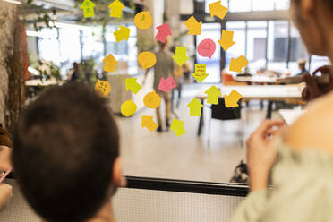 Arrow symbols and speech bubbles on glass wall at office - JCCMF11338