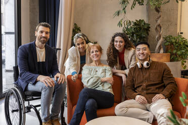 Smiling multiracial business colleagues sitting at co-working space
 - JCCMF11352