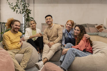 Happy business colleagues sitting on bean bags at office - JCCMF11353