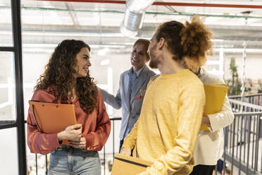 Happy business colleagues walking at co-working space - JCCMF11365