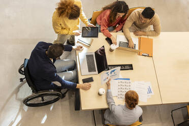 Business colleagues working together at desk in office - JCCMF11372