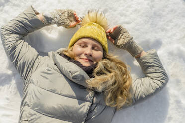 Lächelnde Frau im Schnee liegend mit geschlossenen Augen - KVBF00001