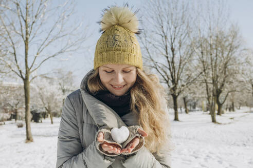 Lächelnde Frau hält herzförmigen Schneeball in der Hand - KVBF00003