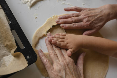 Enkel und Großmutter bei der Zubereitung von Keksen mit Ausstechformen - KVBF00013