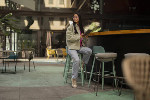 Smiling woman sitting with tablet PC in cafe - JCCMF11415