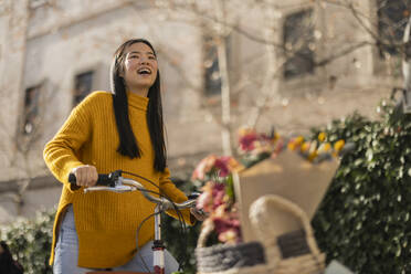 Fröhliche Frau mit Fahrrad an einem sonnigen Tag - JCCMF11426