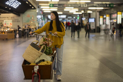 Lächelnde Frau mit Lastenfahrrad am Bahnhof - JCCMF11449