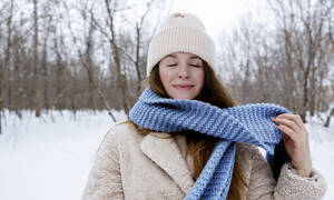 Young smiling woman with eyes closed wearing blue scarf in winter forest - MBLF00273