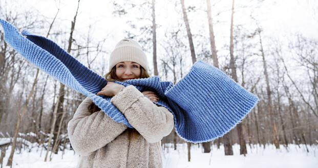 Junge Frau mit blauem Schal steht im Winterwald - MBLF00274