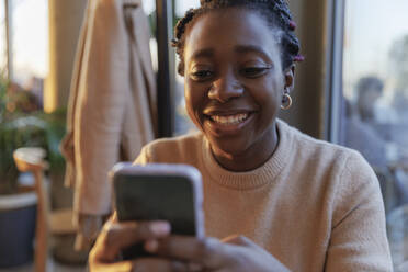 Happy woman using smart phone in cafe - IKF01755