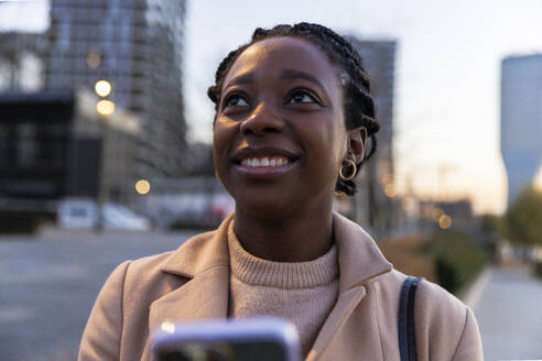 Smiling woman in city at dusk - IKF01757