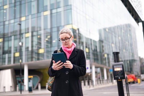 Mature businesswoman using tablet PC on street - AMWF02028