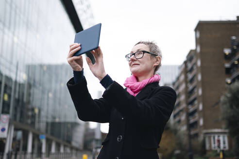 Ältere Geschäftsfrau, die ein Foto mit einem Tablet-PC in der Stadt macht - AMWF02030