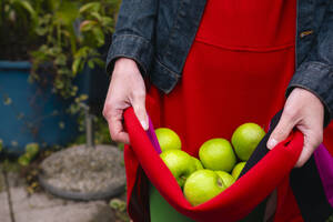Frau mit grünen Äpfeln in der Kleidung - AMWF02033