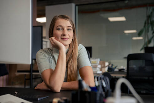 Smiling businesswoman sitting at desk in office - JOSEF23473