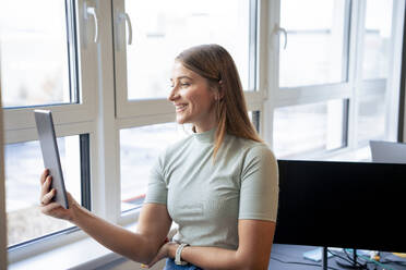 Lächelnde Geschäftsfrau mit Videoanruf auf Tablet-PC im Büro - JOSEF23499