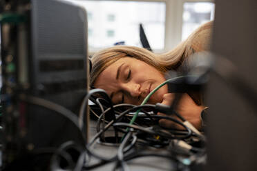 Erschöpfte Geschäftsfrau schläft am Schreibtisch im Büro - JOSEF23503