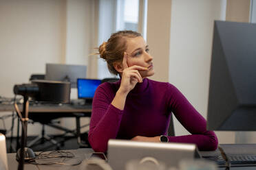 Nachdenkliche Geschäftsfrau, die sich in der Nähe des Computers im Büro auf den Ellbogen stützt - JOSEF23523