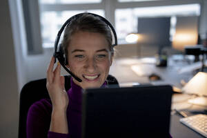 Happy customer service representative wearing headset and talking in office - JOSEF23534